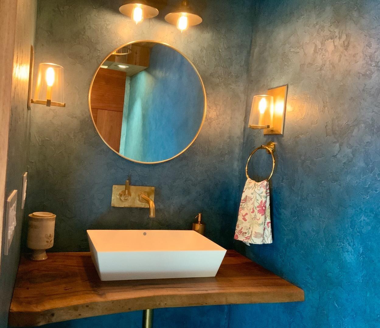Crane home powder room with textured blue walls and warm lighting