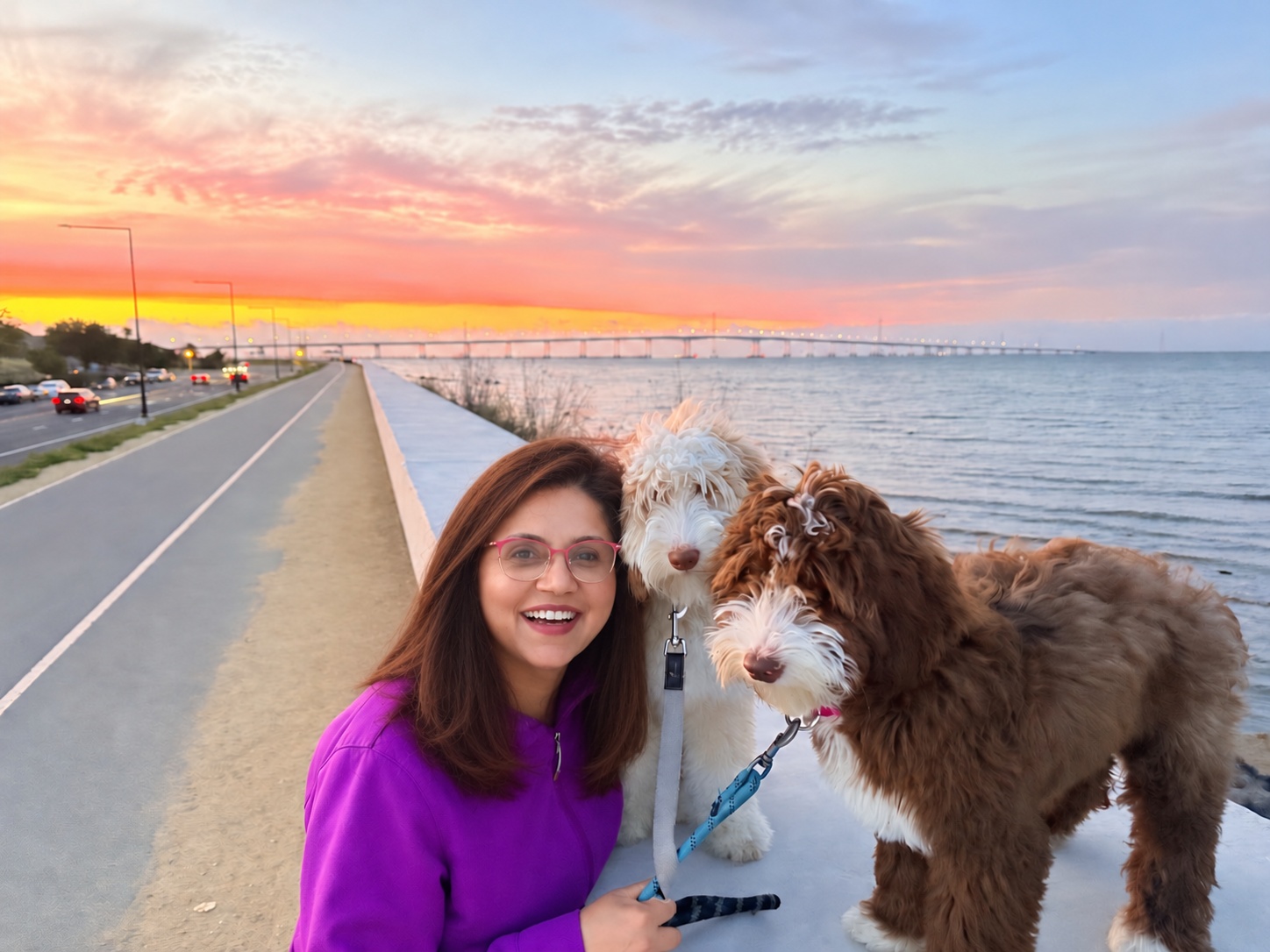 Shiraz Zack with her two dogs beside the water at sunset